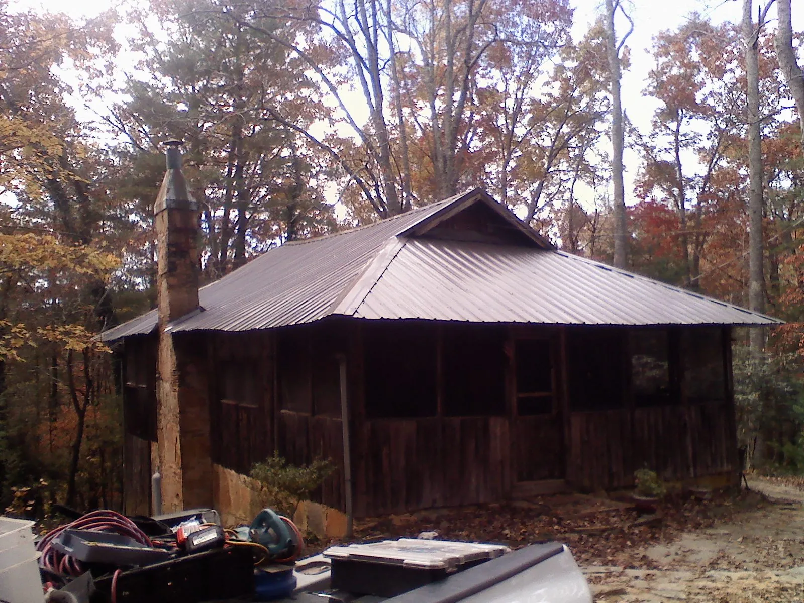 Brown metal hip roof on an old cabin with a stone chimney in Fremont